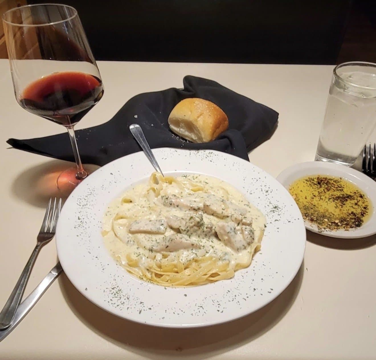 Fettuccine Alfredo with chicken, a glass of red wine and a warm roll at Napoli's in Lincoln, Nebraska